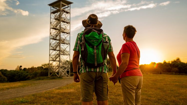 ein Mann und eine Frau blicken von unten auf den Aussichtsturm