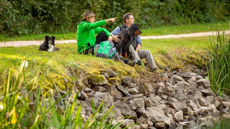 ein Mann, eine Frau und ein Hund sitzen am Itzenplitzer Weiher