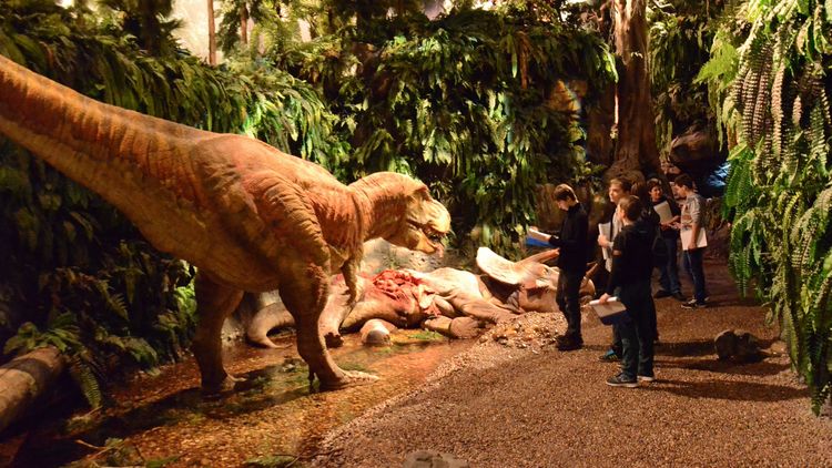 Besucher betrachten eine Dinosaurier Skulptur