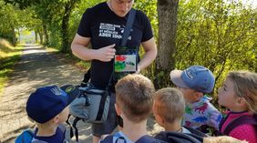 Mann erklärt Kindern etwas zum Thema Ameisen auf einem Tablet