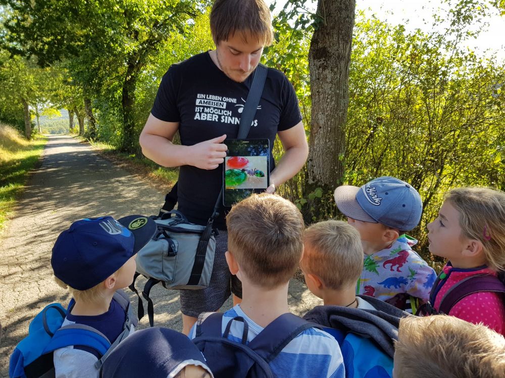 Gästeführer Jan, der Kindern ein Bild zeigt